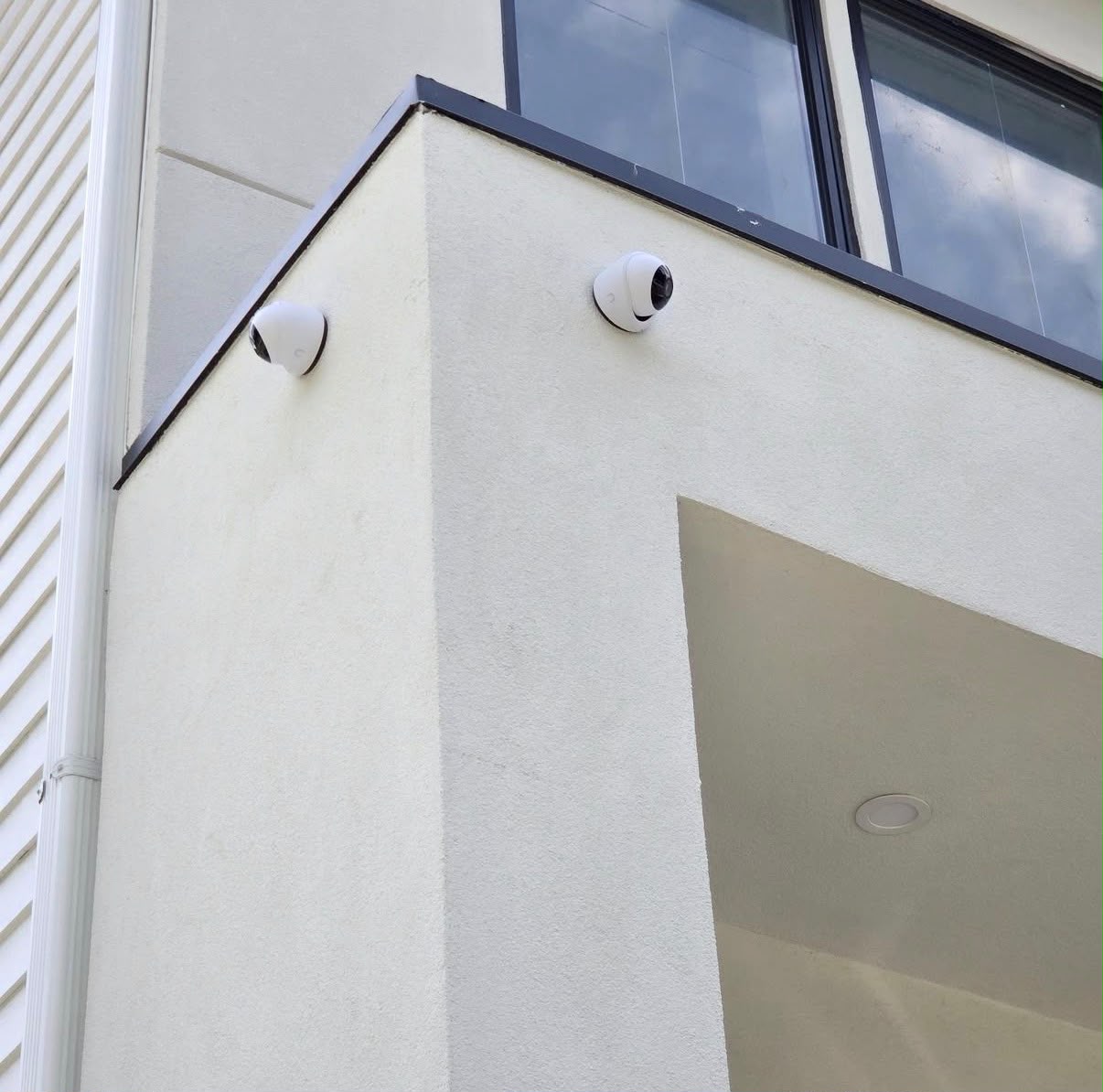 Two dome security cameras cleanly mounted on the corner of a modern stucco building, installed by HD Installs
